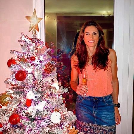 Gabriela Sabatini took a picture with a drink in her hand next to a Christmas tree. 